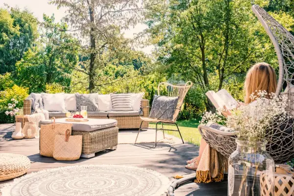 Relaks na tarasie w stylu boho: rattanowe meble, plecione kosze i okrągły dywan tworzą przytulną przestrzeń. Inspiracje dla Twojego ogrodu.