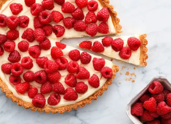 Tarta z malinami i mascarpone, ozdobiona białą czekoladą, kusi świeżością i kremowym nadzieniem.
