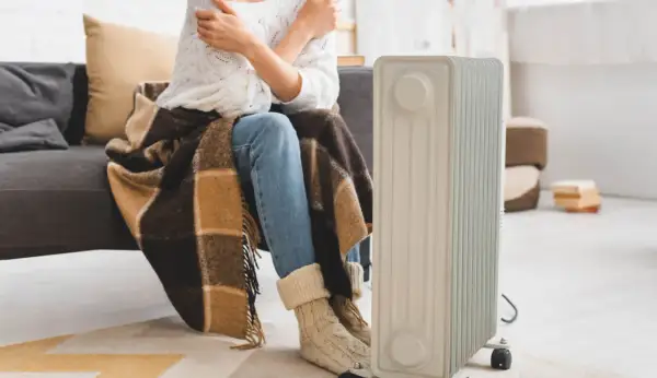 Zastanawiasz się, jaki grzejnik elektryczny do pokoju 25m2 będzie najlepszy? Ta osoba otulona kocem i w ciepłych skarpetach czeka na ciepło z nowego grzejnika.