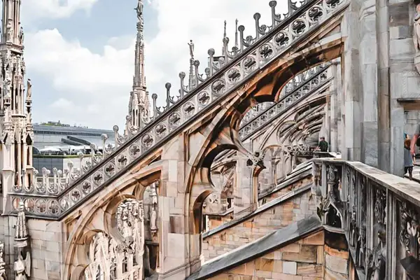 Gotycka architektura Duomo, z której słynie Mediolan, z detalami rzeźb i iglicami na tle błękitnego nieba.