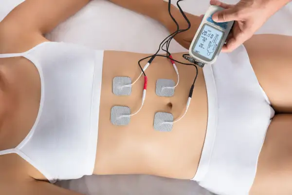 Elektrostymulacja mięśni brzucha za pomocą urządzenia z elektrodami.