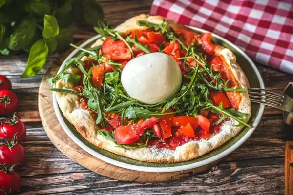 Pizza mit frischen Tomaten, Rucola und einer Kugel Burrata, die Lust auf burrata selber machen macht.