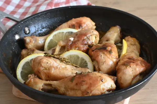 Cosce di pollo al limone succulente e dorate, cotte in padella con fette di limone e erbe aromatiche.