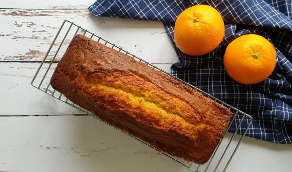 Gâteau doré sur grille, prêt à être dégusté. Une recette gâteau facile et originale, avec des oranges fraîches à côté.