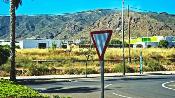 Señal de ceder el paso en una carretera con montañas al fondo.