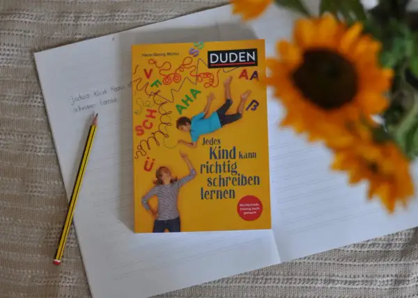 Ein Duden-Buch mit dem Titel "Jedes Kind kann richtig schreiben lernen" liegt auf einem Notizbuch. Ein Bleistift liegt daneben. Rechtschreib-training leicht gemacht.