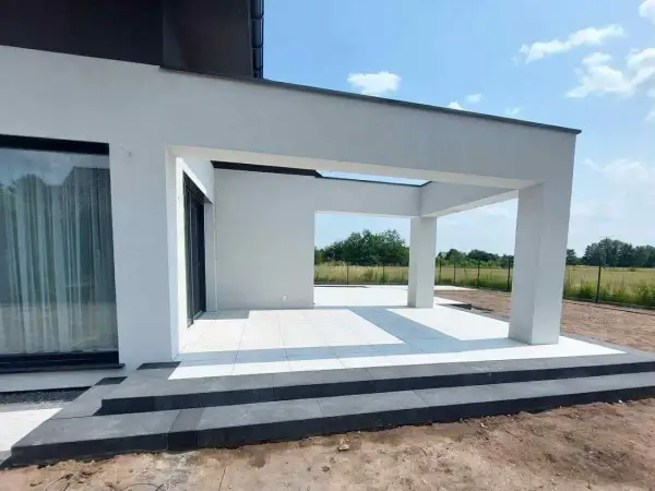 Nowe schody i taras z białej kostki betonowej przy nowoczesnym domu.