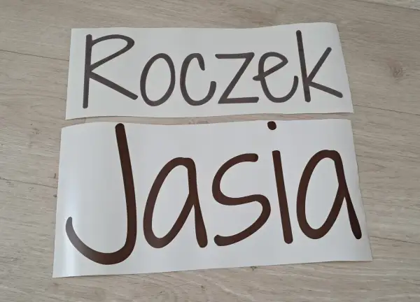 Napis "Roczek Jasia" na białych arkuszach, gotowy do dekoracji przyjęcia.