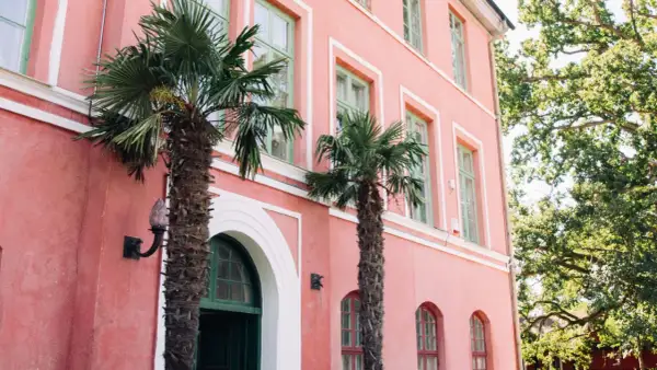 Hoby Kulle Herrgård i rosa nyanser med gröna fönster och palmer som ger en oväntad känsla.