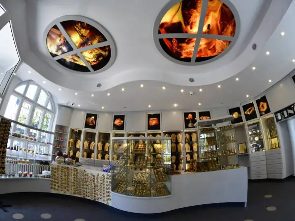 Wnętrze muzeum bursztynu Kołobrzeg. W gablotach błyszczą złote ozdoby, a na suficie zdobią okrągłe panele z bursztynu.