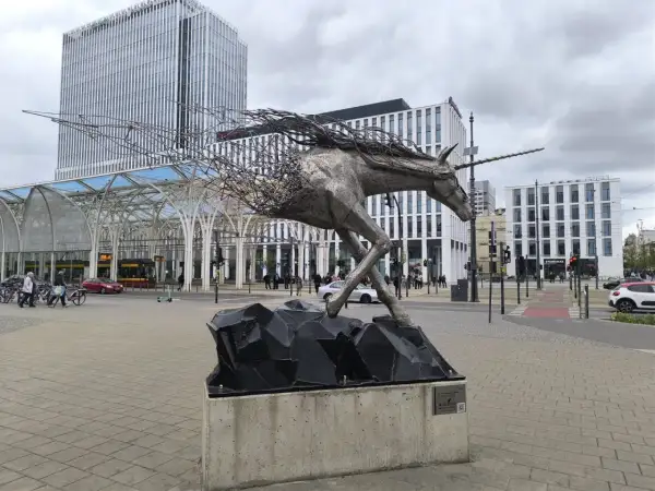 Metalowy jednorożec na skalnej podstawie, symbolizujący dynamikę i nowoczesność, na tle architektury Piotrkowska Łódź.