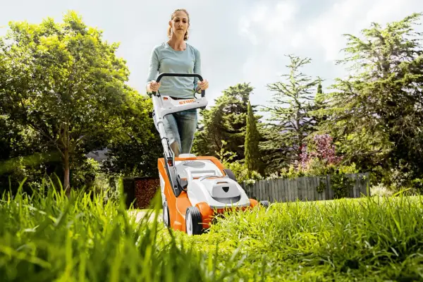 Mujer cortando césped con cortacésped eléctrico. Consejos para cortar el césped: mantén la cuchilla afilada y la altura adecuada.