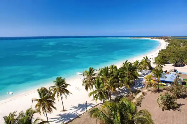 Playa caribeña con palmeras y aguas turquesas, un paraíso antes de la época de huracanes en Cuba.