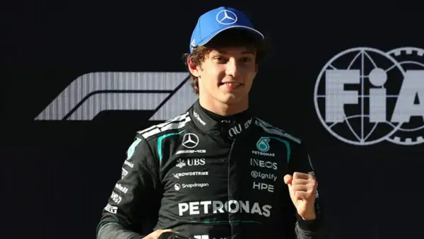 George Russell, piloto de Fórmula 1, celebra con un puño cerrado. Las noticias de Fórmula 1 lo muestran con el logo de Mercedes y FIA.