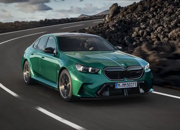 Zielone m5 bmw pędzi po krętej drodze wśród skalistych krajobrazów.