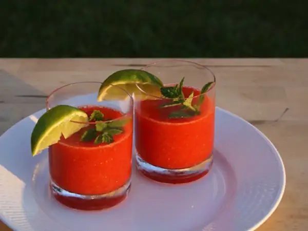 Två glas med en uppfriskande strawberry daiquiri, garnerade med lime och mynta. Perfekt för en solig sommardag.