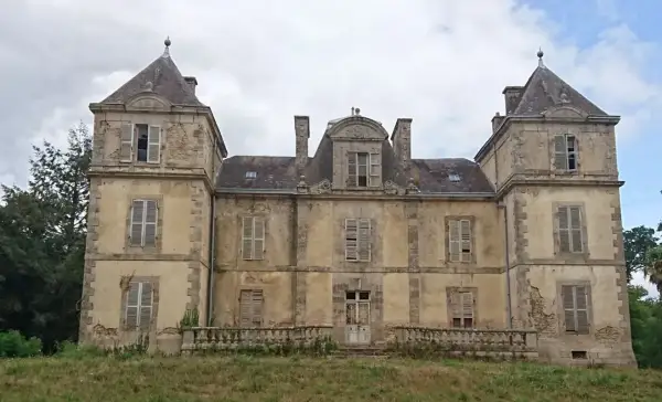 Vaste manoir abandonné en Bretagne, aux façades décrépites et aux volets clos, témoignant d'une histoire oubliée.
