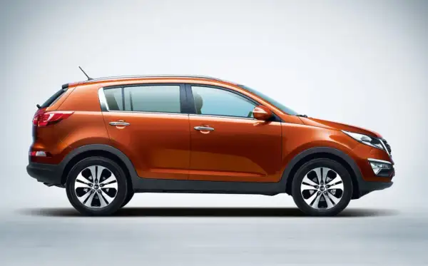 Pomarańczowy Kia Sportage 2015, widok z boku, na jasnym tle. Stylowy SUV gotowy na przygodę.