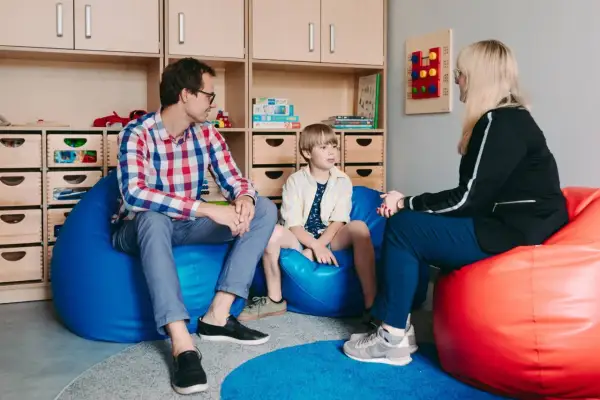 Ojciec, syn i terapeutka rozmawiają w przytulnym pokoju. To ważny moment terapii dla nastolatków, gdzie budowane jest zaufanie i wsparcie.