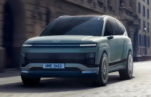 Przyszłościowy Hyundai Ioniq 9 w kolorze miętowym przemierza miejskie ulice, prezentując swój unikalny design i innowacyjne oświetlenie.