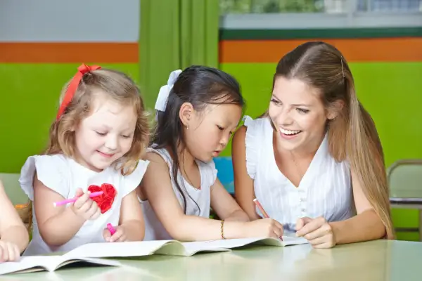 Lehrerin hilft Kindern beim Malen. Ein schönes lerngeschichte beispiel, wie Kinder kreativ werden.