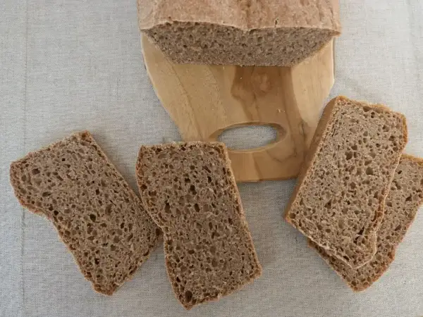 Kromki ciemnego chleba na desce, aż chce się jeść, ale potem może pojawić się zgaga po chlebie.