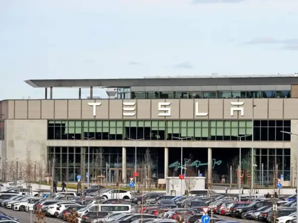 Tesla-Fabrik mit vielen Autos auf dem Parkplatz. Der Tesla-Betriebsrat vertritt die Interessen der Belegschaft.