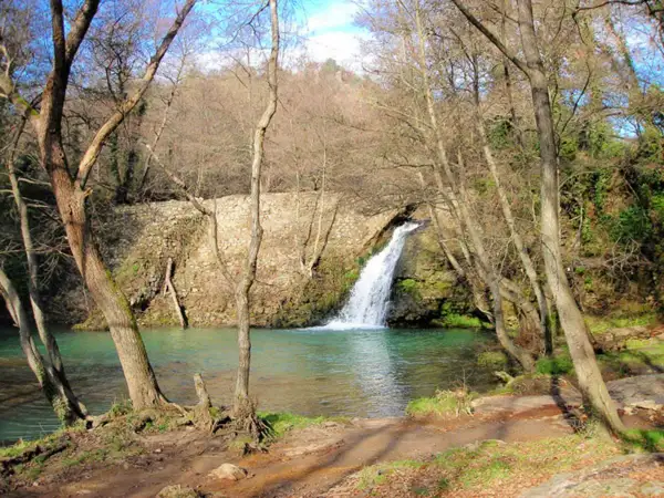 Cascata della mola di Oriolo, con acque turchesi e alberi spogli che incorniciano la scena.