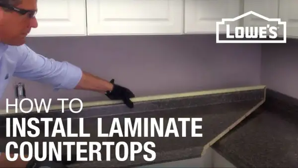 Learn how to install laminate countertops with this helpful guide. A person in gloves is shown working on a countertop.