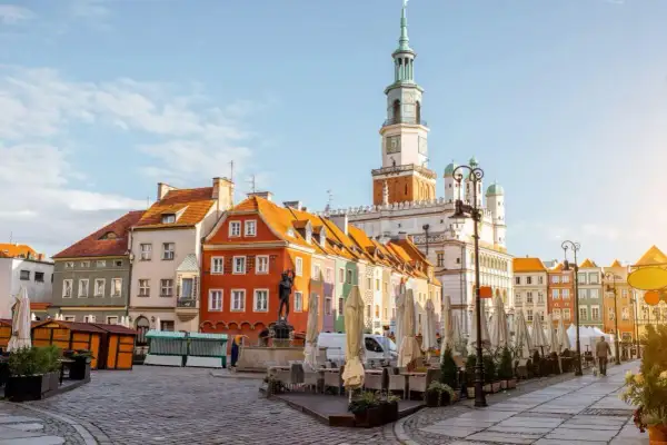 Kolorowe kamienice na Starym Rynku w Poznaniu, gdzie czeka na Ciebie poznań miasto doznań. Ratusz góruje nad placem pełnym ogródków kawiarnianych.