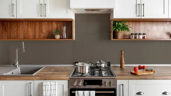 Cocina moderna con pared mitad azulejo gris y mitad estante de madera. Ollas en la estufa, grifo y plantas decorativas.