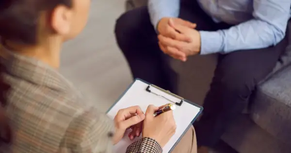 Sesja terapeutyczna, gdzie psychoterapeuta notuje ważne informacje. To obraz postępu w kierunku regulacji zawodu, jak ustawa o zawodzie psychoterapeuty.
