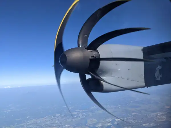 Wirujący śmigłowiec samolotu z efektem rolling shutter nad miastem i górami w oddali.