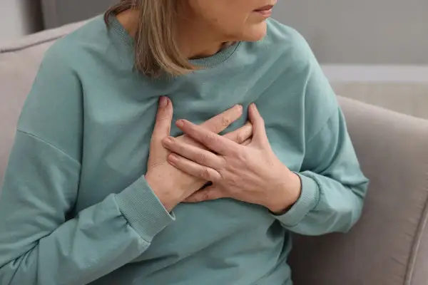 Kobieta trzymająca się za serce. Badanie poziomu lipoproteiny jest kluczowe dla oceny ryzyka chorób serca.