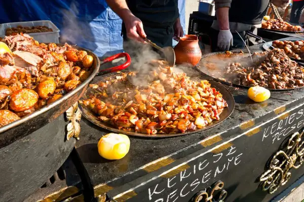 Varm mat ångar från stora pannor på en marknad i Budapest. Kött och grönsaker tillagas.