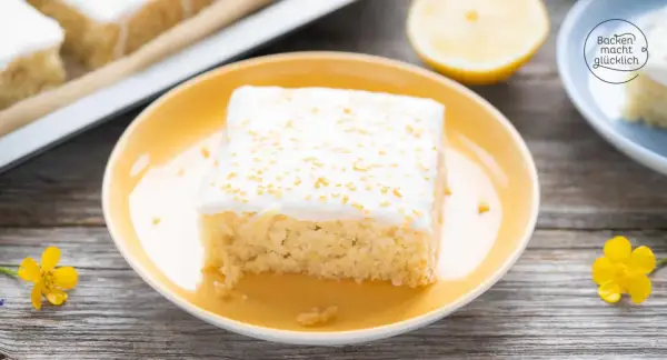 Ein Stück saftiger, veganer Zitronenkuchen mit weißer Glasur und goldenen Streuseln auf einem gelben Teller.