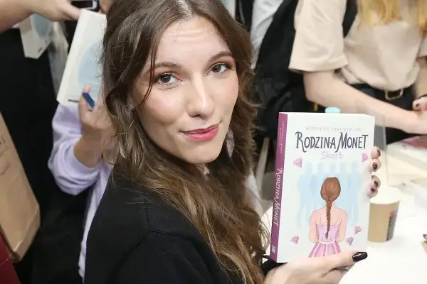 Kobieta trzyma książkę "Rodzina Monet - Skarb" z wizerunkiem dziewczyny z warkoczem.