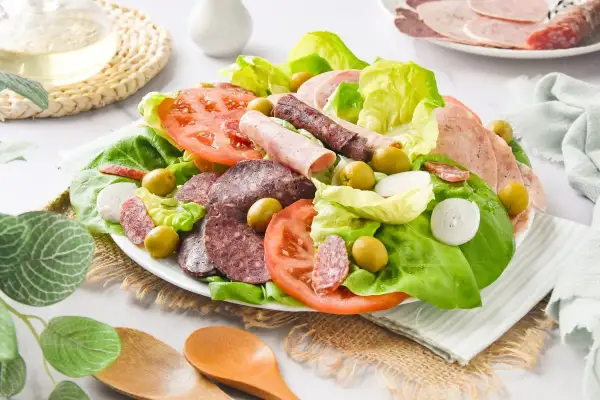 Amanida catalana con lechuga, tomate, aceitunas, cebolla y embutidos variados.