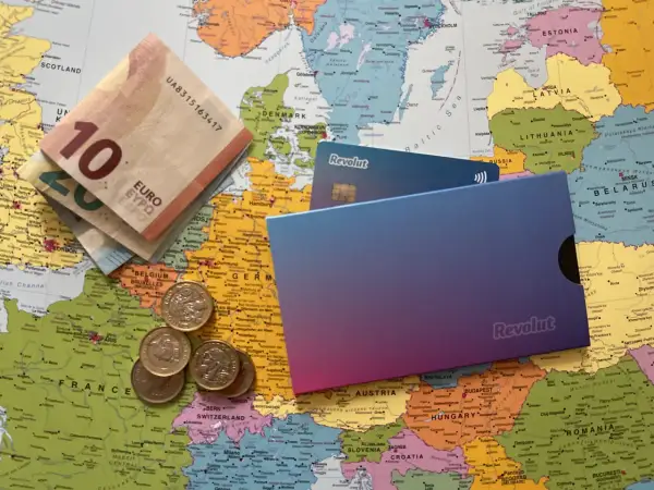 Euro banknoty, monety i karty Revolut leżą na mapie Europy. Czy Revolut jest darmowy? Sprawdź, zanim wyruszysz w podróż!