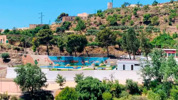 Piscina municipal en el oeste de Almería, rodeada de vegetación y colinas. Un oasis refrescante bajo el sol andaluz.
