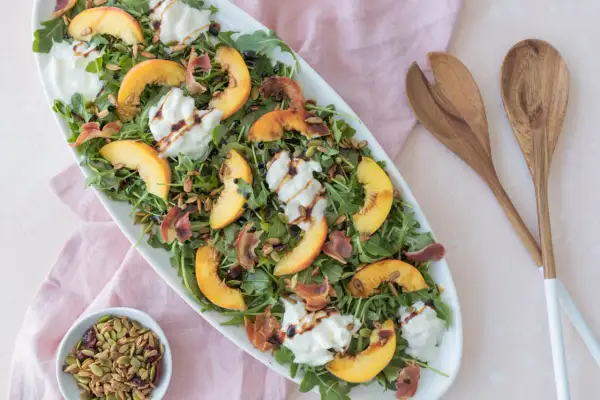 Salade d'été avec pêche, burrata crémeuse, roquette, prosciutto croustillant et vinaigre balsamique. Un délice !