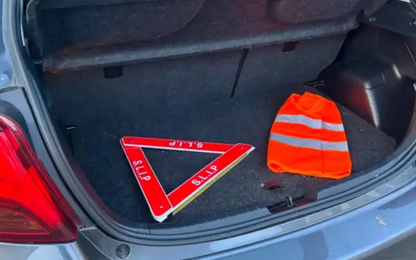 Triangle de signalisation et gilet de haute visibilité dans un coffre de voiture, prêts pour la signalisation dépassement chargement arrière.