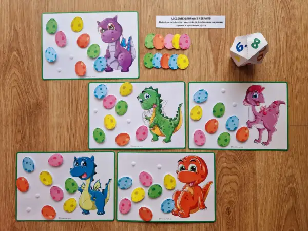 Zabawa edukacyjna na dzień dinozaura w przedszkolu: kolorowe jajka do przyklejania na planszach z dinozaurami.