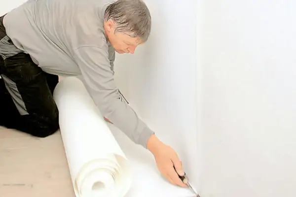 Man skär tapet för renovering. Noggrant arbete med renoveringstapet skarvar för ett perfekt resultat.