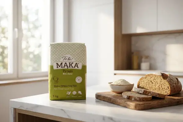 Torba mąki żytniej, bochenek chleba i miseczka z mąką na blacie kuchennym.
