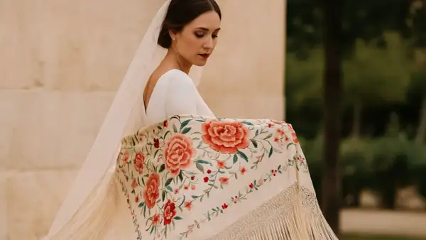 Novia con velo y mantón bordado con flores, mostrando elegantes formas de poner un mantón.