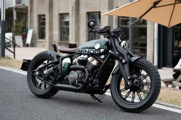 Zielony, stylowy chopper Benda, najmocniejszy chopper 125, z brązowym siedzeniem i czarnymi felgami, zaparkowany na ulicy.