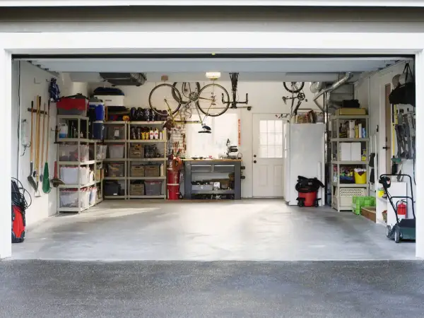Organizzazione garage con scaffalature, biciclette appese e attrezzi. Ottime idee garage fai da te per uno spazio funzionale.