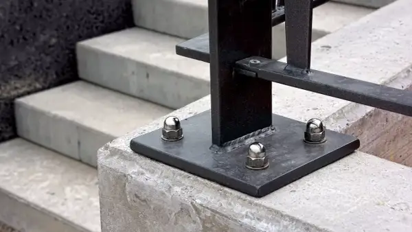 Base de barandilla metálica fijada con taco químico Sika a escalones de hormigón.