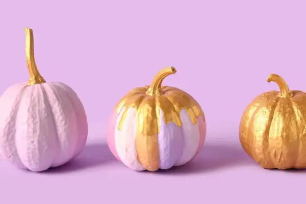 Tre zucche dipinte in tonalità pastello e oro, con un tocco scintillante.